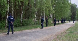 Policjanci stoją przed kompleksem leśnym