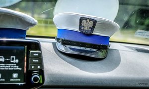 foto poglądowe, czapka policjanta ruchu drogowego leżąca na desce rozdzielczej radiowozu.