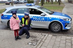 policjantka ruchu drogowego z dzieckiem w tle radiowóz.