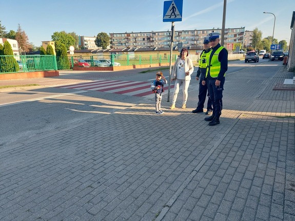 policjanci w rejonie przejścia dla pieszych z dzieckiem i opiekunem.