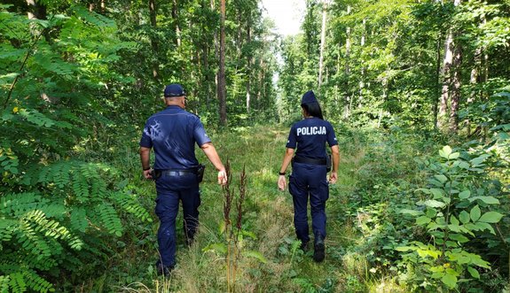 policjant i policjantka patrolują las.