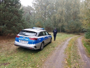 policjantka podczas obserwcji terenu leśnego w tle radiowóz.
